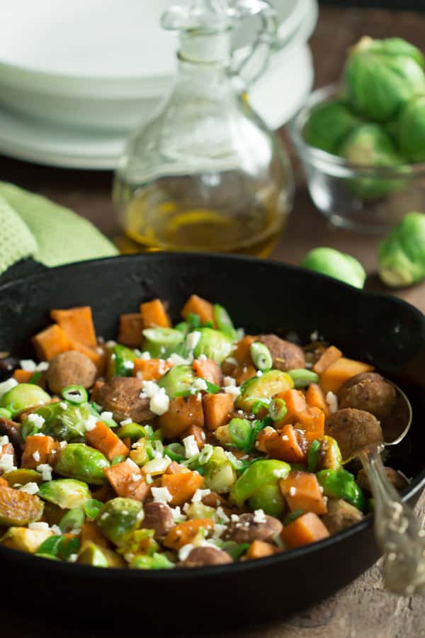 close up of a cast iron skillet containing sweet potato and brussels sprouts