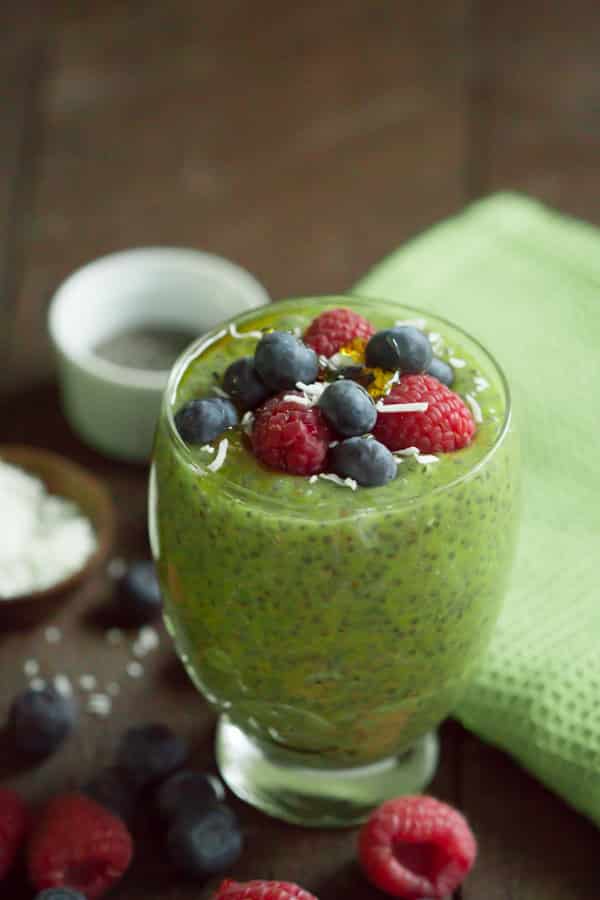 Kiwi Chia Pudding topped with blueberries, raspberries, and coconut in a glass serving cup.