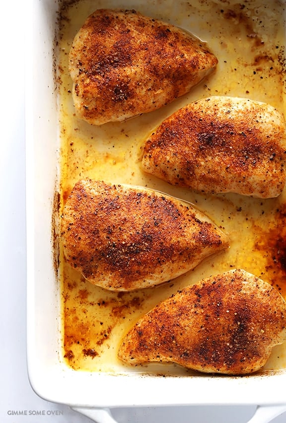 An overhead view of seasoned Baked Chicken Breasts inside of a white casserole dish.