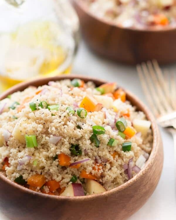 Close up of a couscous salad on a wooden bowl.