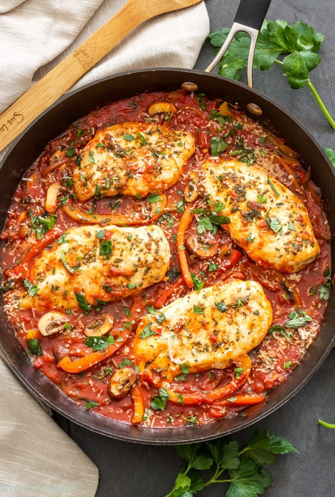 Overhead view of Skillet Chicken Cacciatore garnished with fresh herbs inside a large skillet.
