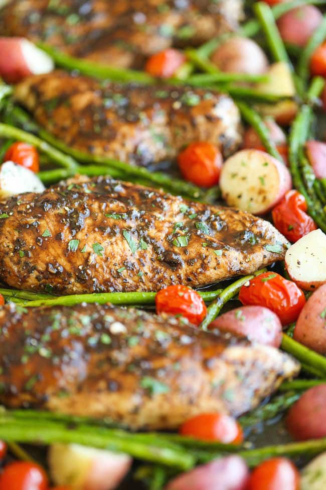 A close-up of Honey Balsamic Chicken Breasts, baby potatoes, tomatoes, and asparagus.