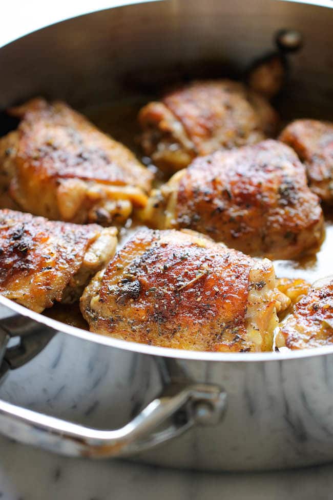 A close-up view of seared lemon chicken in a large metal skillet.