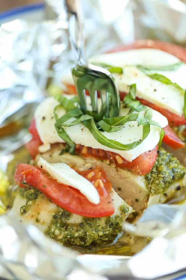 Chicken topped with pesto, tomatoes, mozzarella cheese, and fresh basil inside a foil packet.