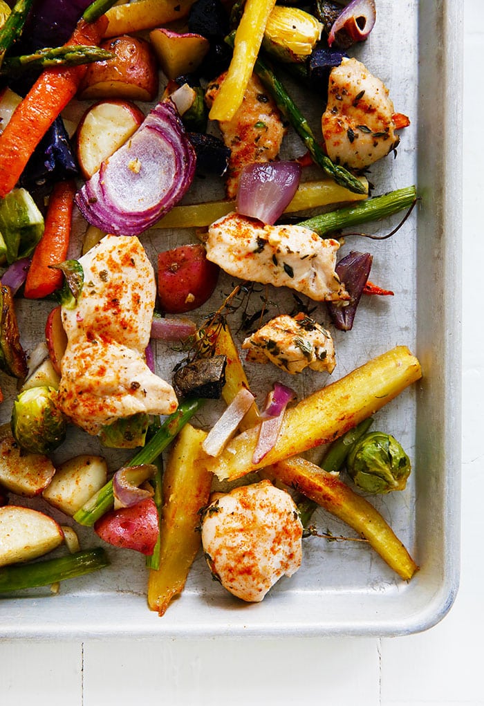 Â An overhead view of chicken and colorful mixed vegetables on a baking sheet.
