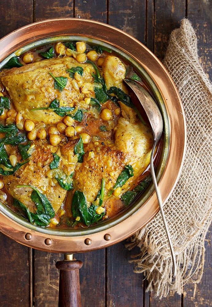 Indian-spiced chicken With Chickpeas and Spinach inside of a skillet with a serving spoon in it.