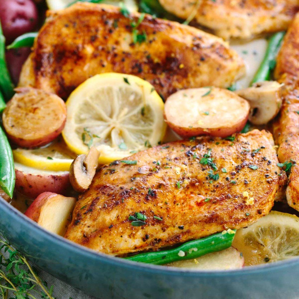 Lemon chicken with potatoes, mushrooms, and green beans in a large skillet.