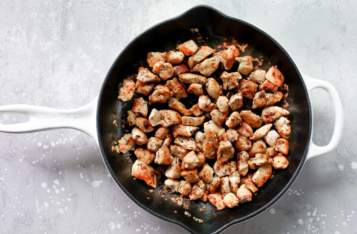 Pieces of chicken cooking in a skillet.