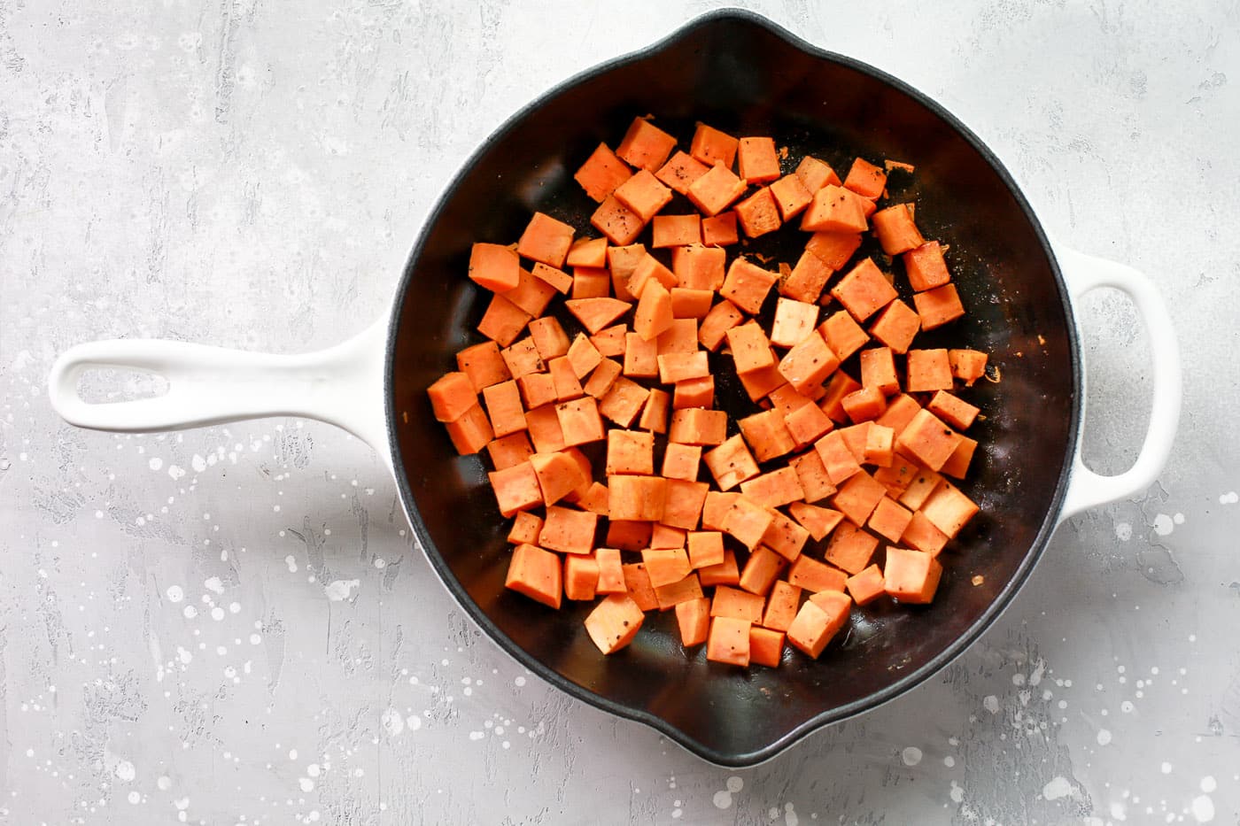 Diced sweet potatoes cooking in a skillet.
