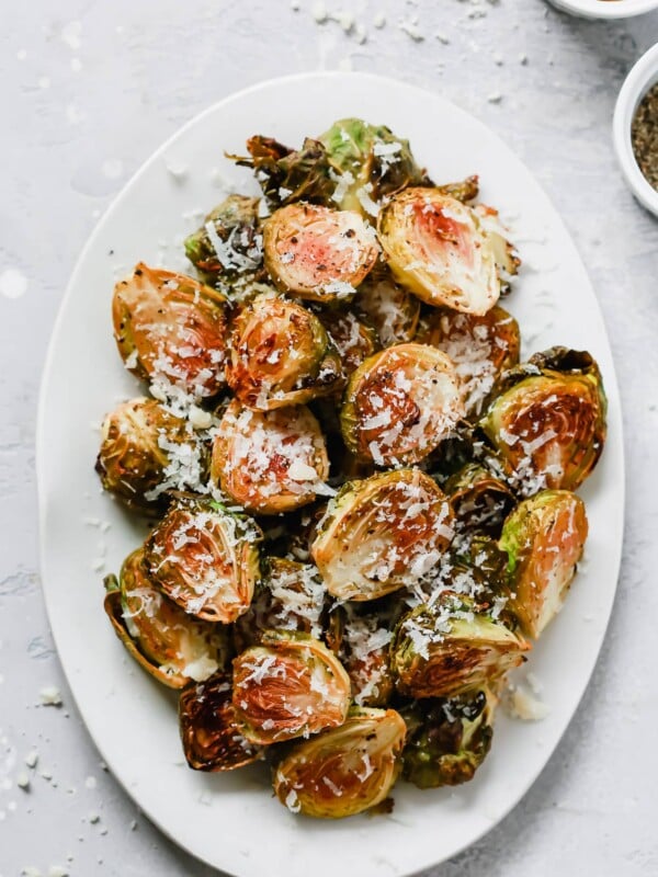 Overhead photo of a white serving platter with garlic parmesan roast brussels sprouts.