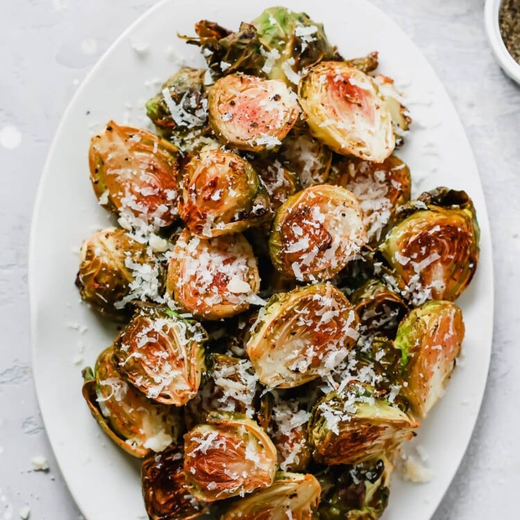 Overhead photo of a white serving platter with garlic parmesan roast brussels sprouts.