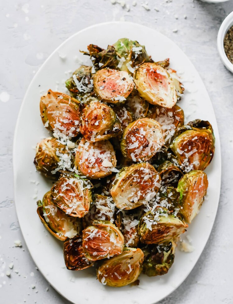 Overhead photo of a white serving platter with garlic parmesan roast brussels sprouts.