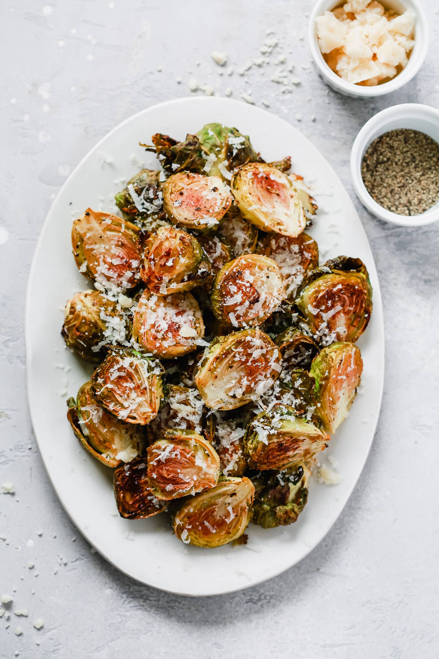 Overhead photo of a white serving platter with garlic parmesan roast brussels sprouts.