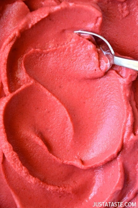 A closeup of strawberry frozen yogurt with a silver spoon in it.