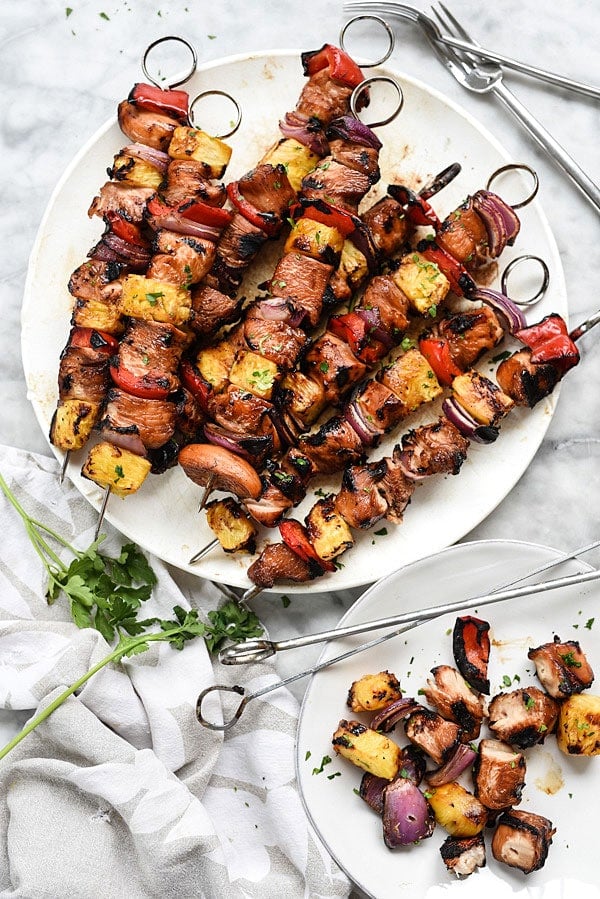 overhead view of Hawaiian Chicken Skewers on a white plate on a marble board.