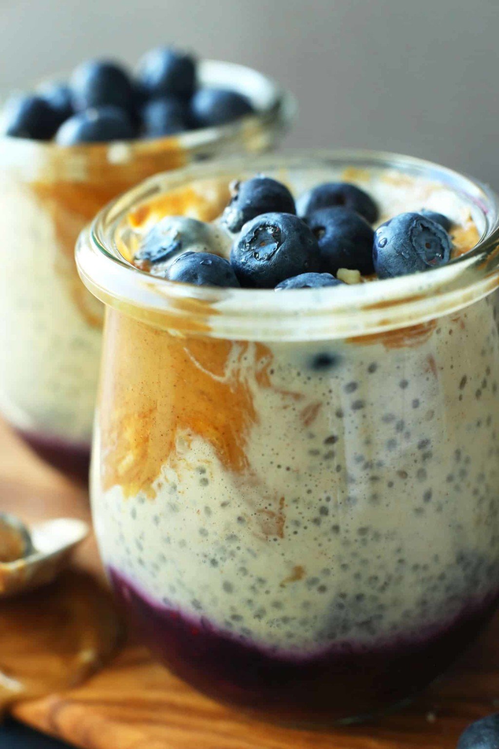 Swirled peanut butter and jelly chia pudding topped with blueberries in a glass serving cup.