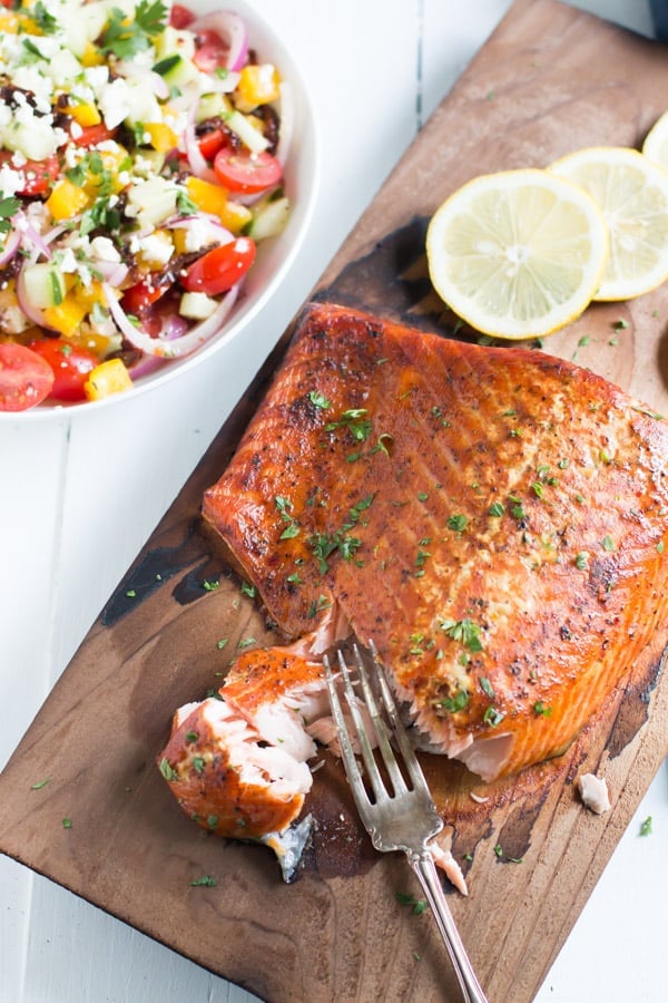 A wooden cutting board with cedar plank salmon.