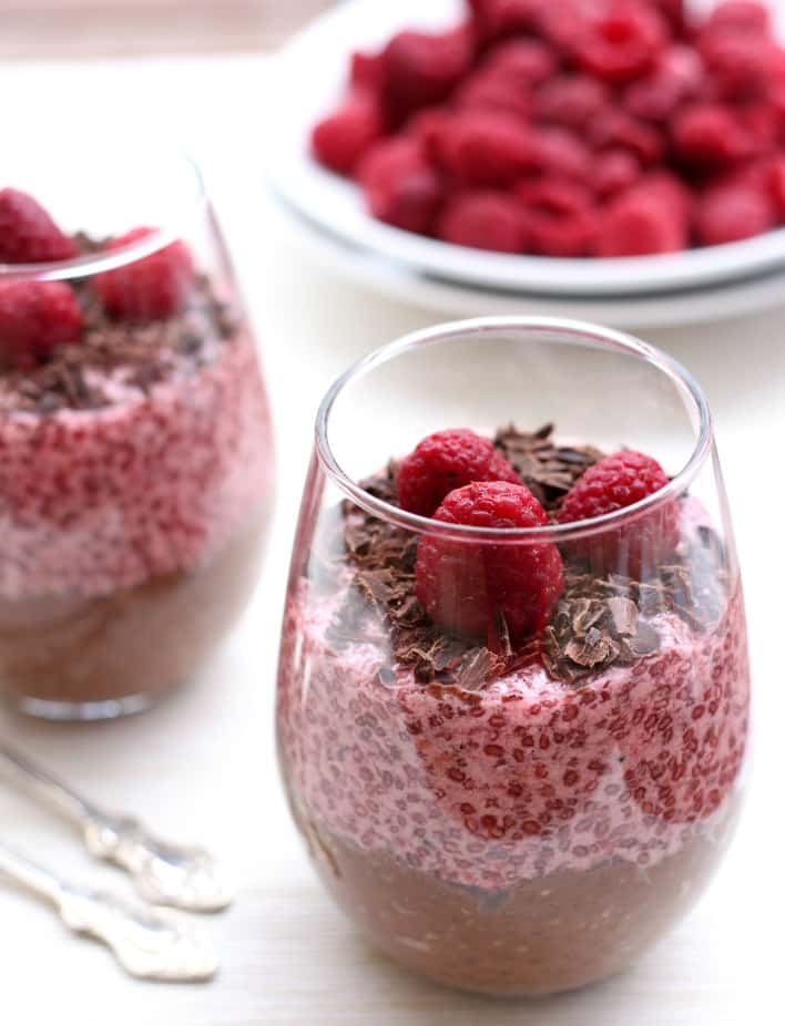 Chocolate and raspberry chia pudding topped with raspberries and chocolate chips in a serving glass.