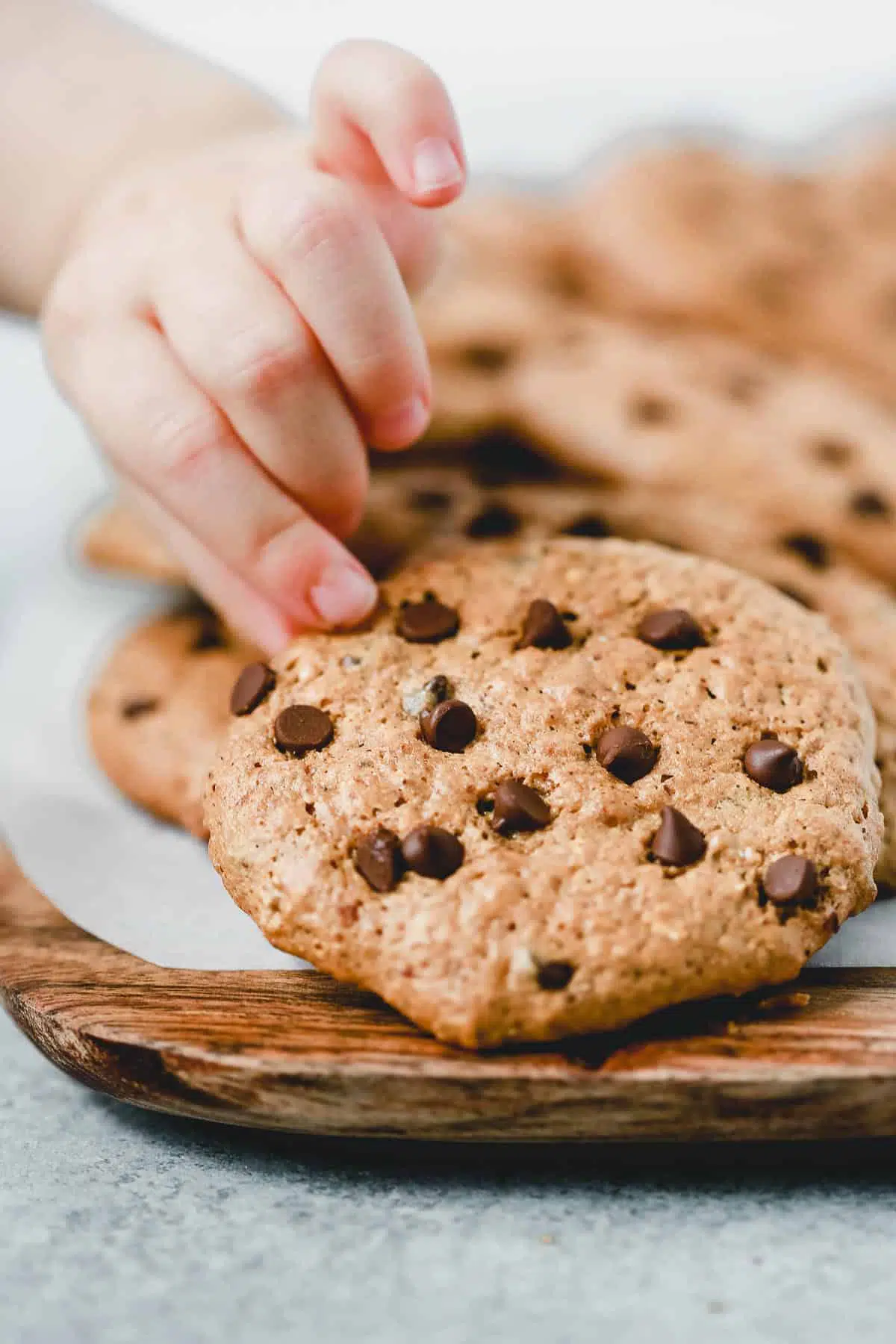 child\'s fingers pulling an almond butter chocolate chip cookie from a tray