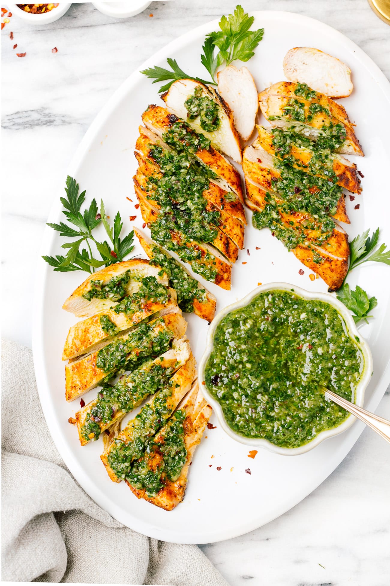 overhead chicken breast with chimichurri sauce on a white plate