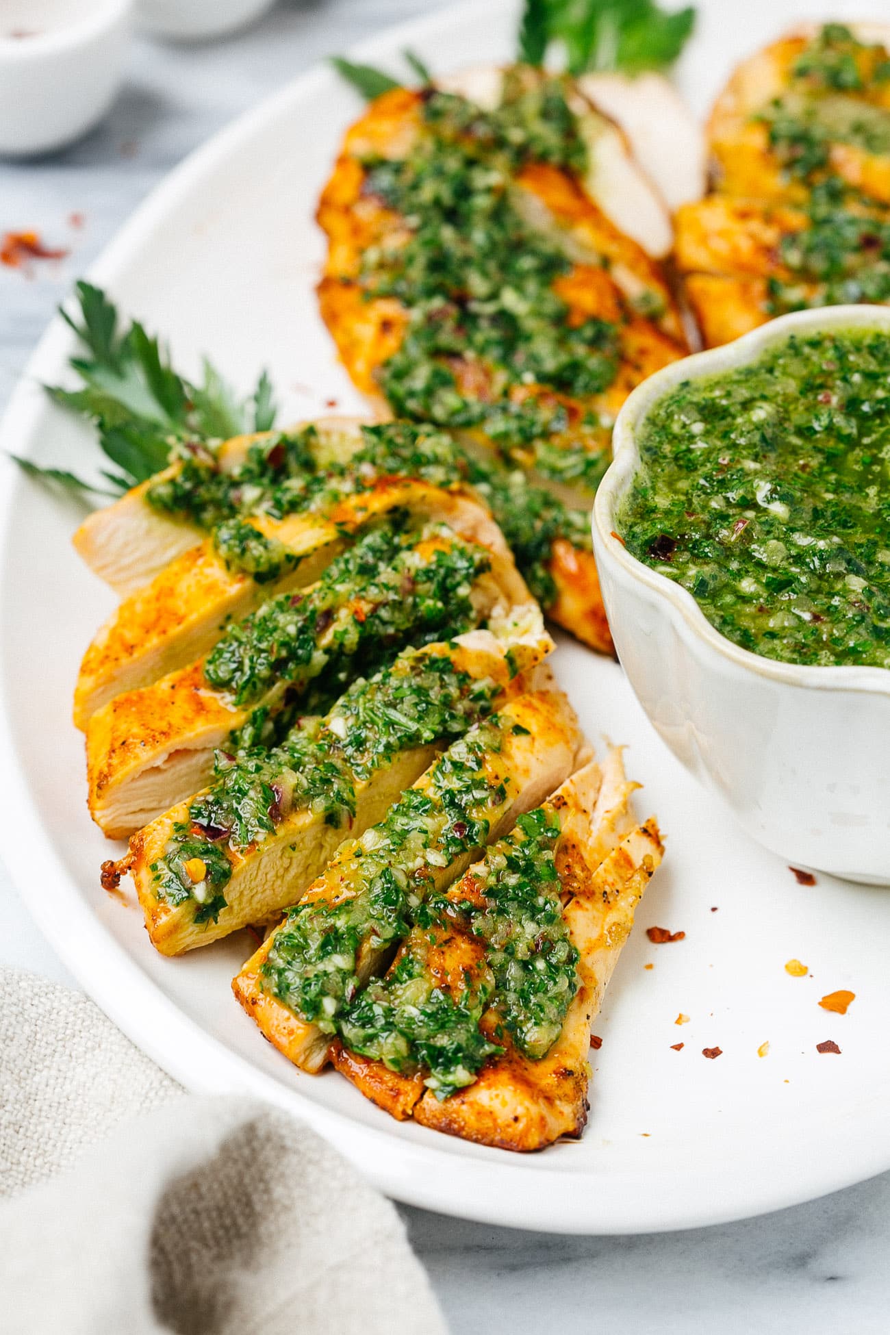 overhead chicken breast with chimichurri sauce on a white plate