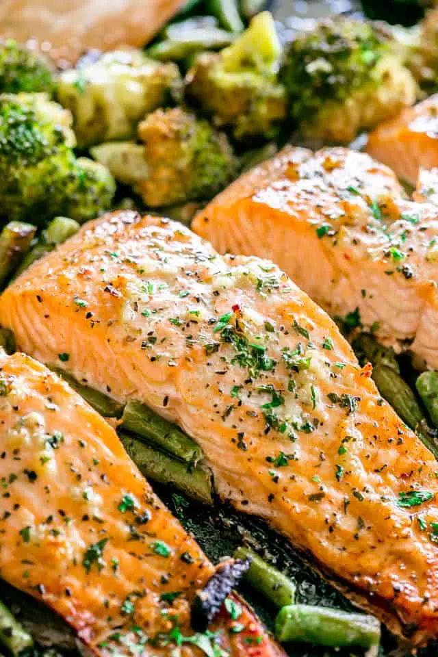 3 pieces of fish in a baking sheet with gree beans and broccoli