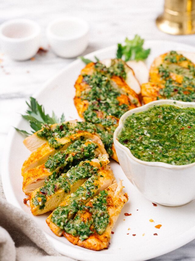 overhead chicken breast with chimichurri sauce on a white plate