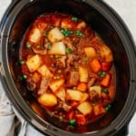 Healthy slow cooker beef stew inside of a black slow cooker bowl.