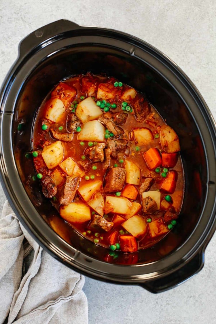 Healthy slow cooker beef stew inside of a black slow cooker bowl.