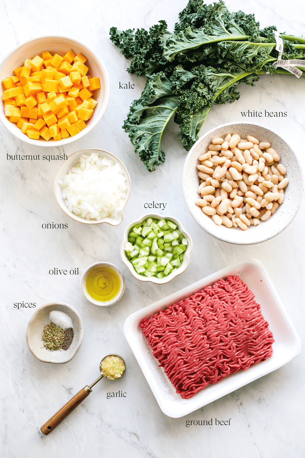 Ingredients for white bean and kale soup arranged on a countertop.