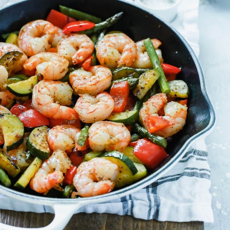 A white cast iron with shrimp and vegetables inside.