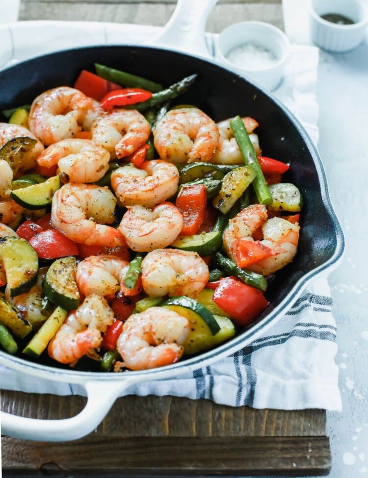 A white cast iron with shrimp and vegetables inside.