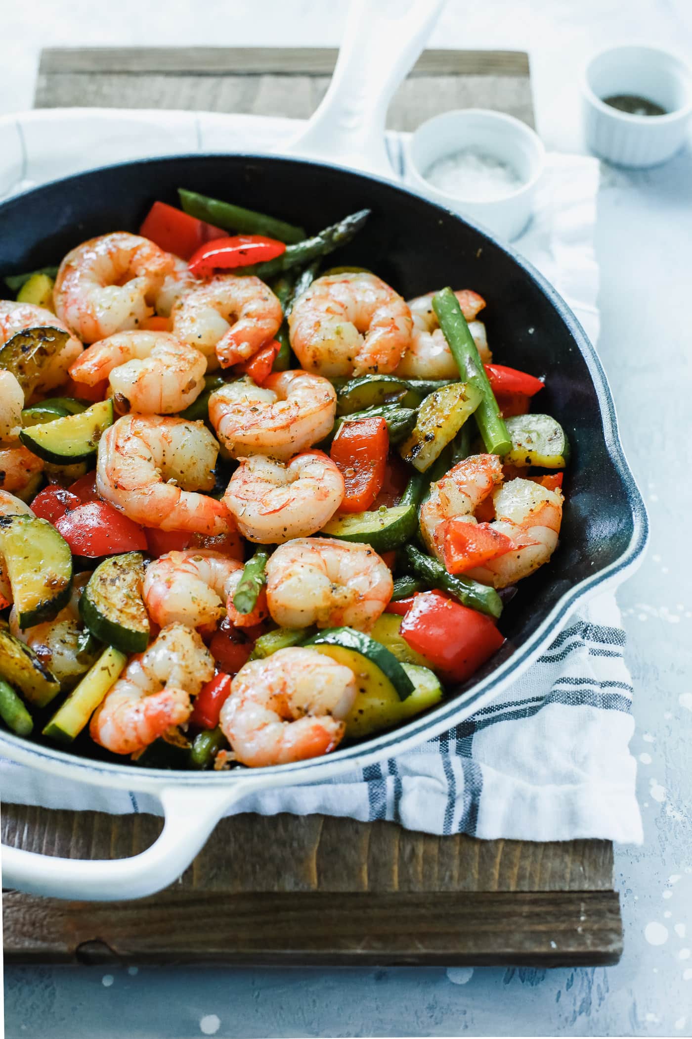 A white cast iron with shrimp and vegetables inside.