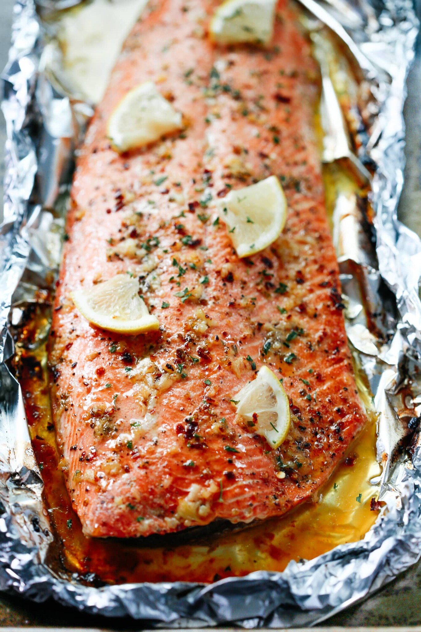 Closeup Baked Salmon with lemon slices and garlic butter sauce on the top.