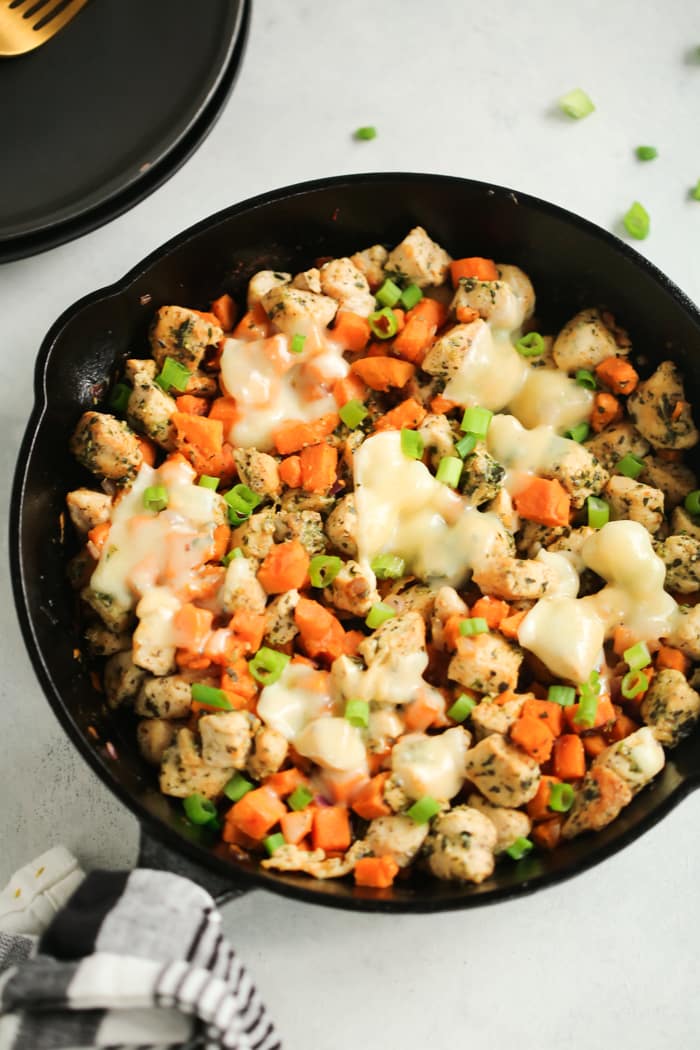 Overhead view of black cast iron with sweet potato pesto chicken.