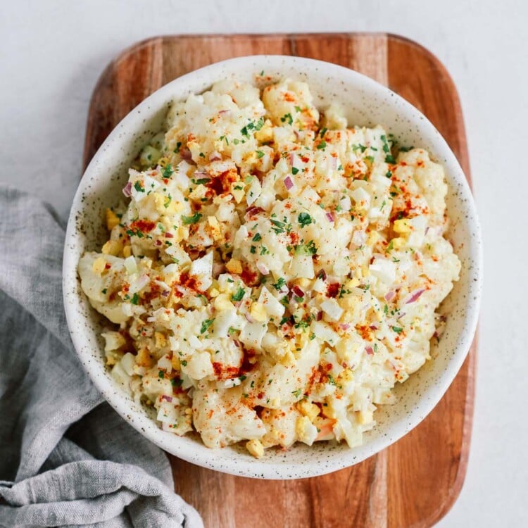 Overhead shot of cauliflower potato salad on on a wooden serving board