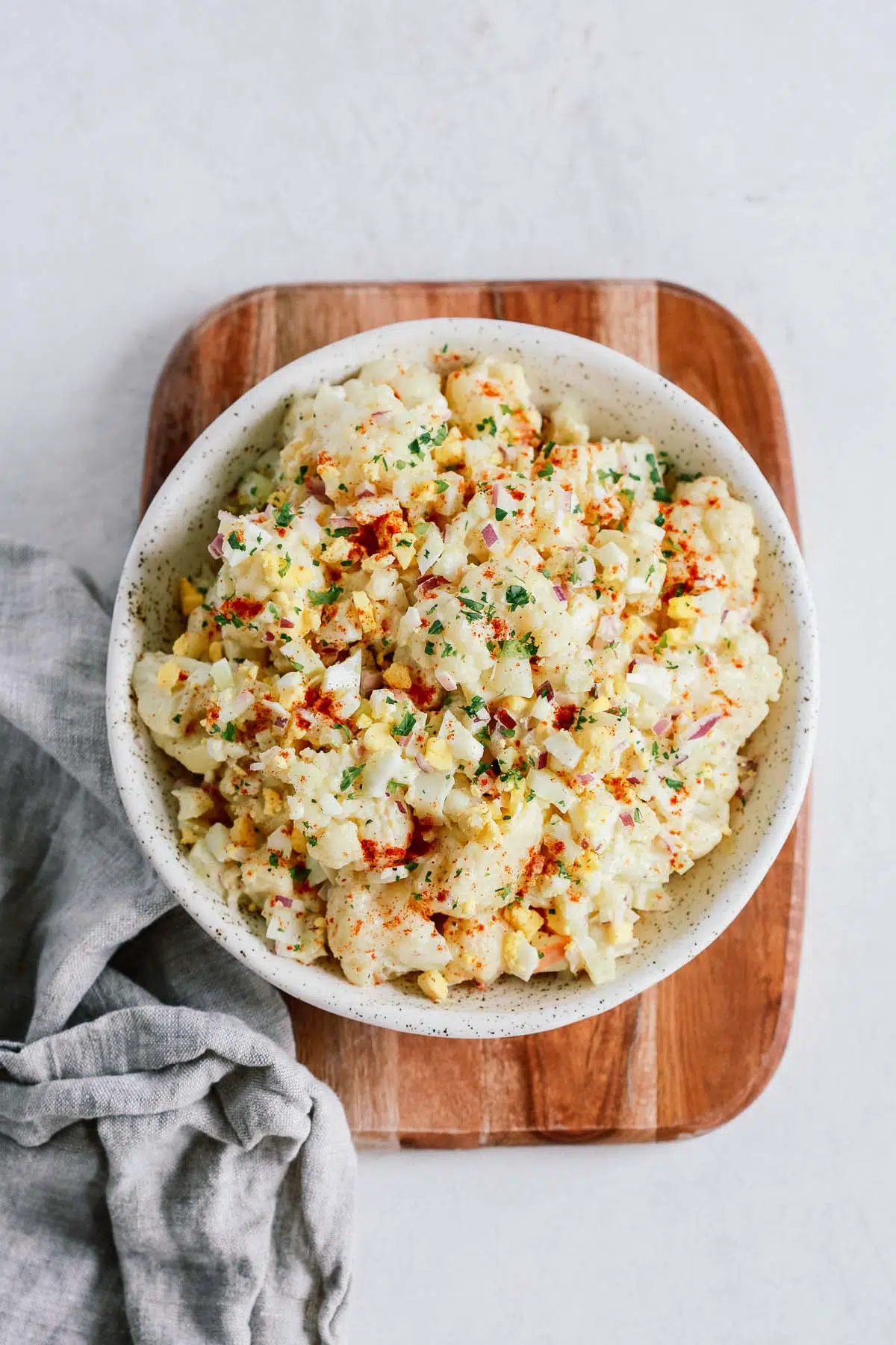 Overhead shot of cauliflower potato salad on on a wooden serving board