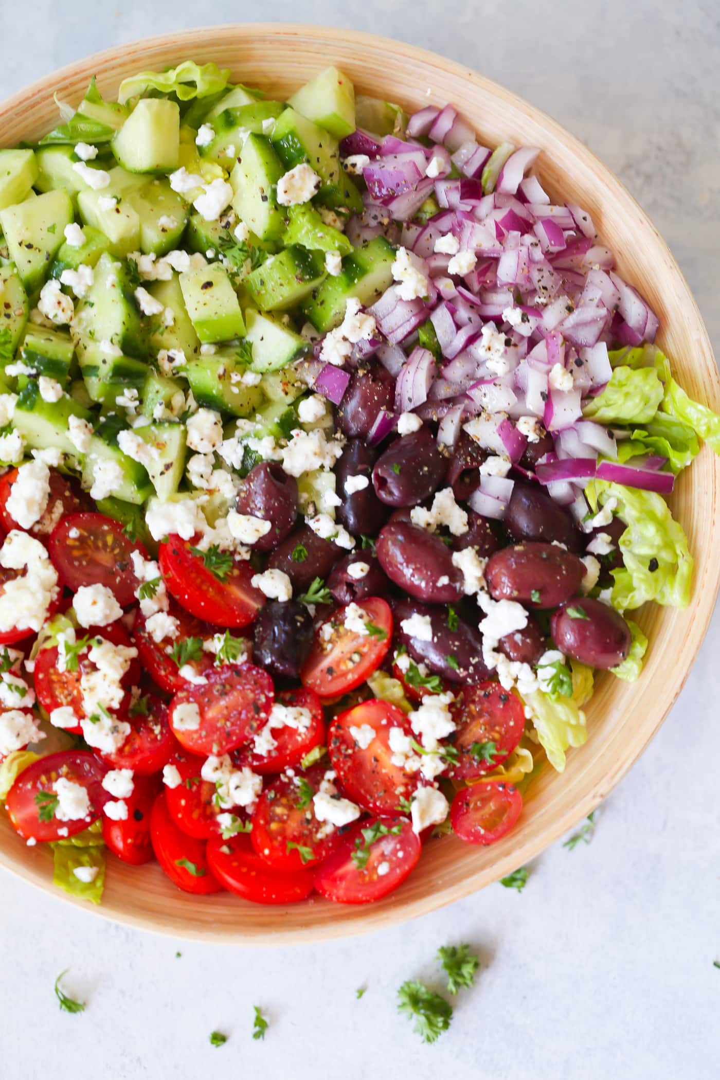 Easy Mediterranean Chopped Salad - Enjoy this Easy Mediterranean Chopped Salad made with red onions, black olives, lettuces, cucumber, cherry tomatoes, feta cheese and light lemon dressing! Mediterranean salad in a large bowl.