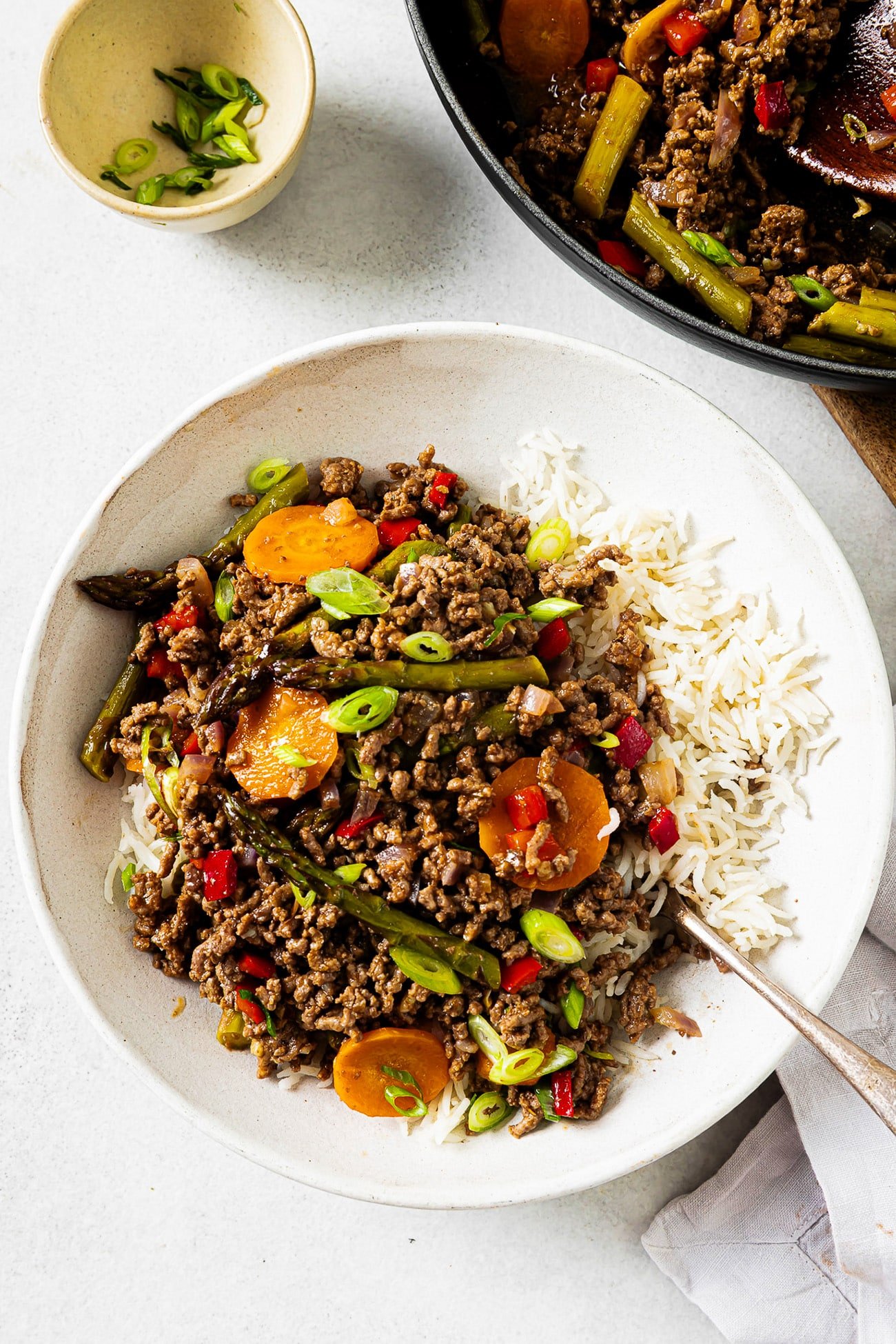 Overhead view of ground beef with vegetables and rice served in a white bowl.