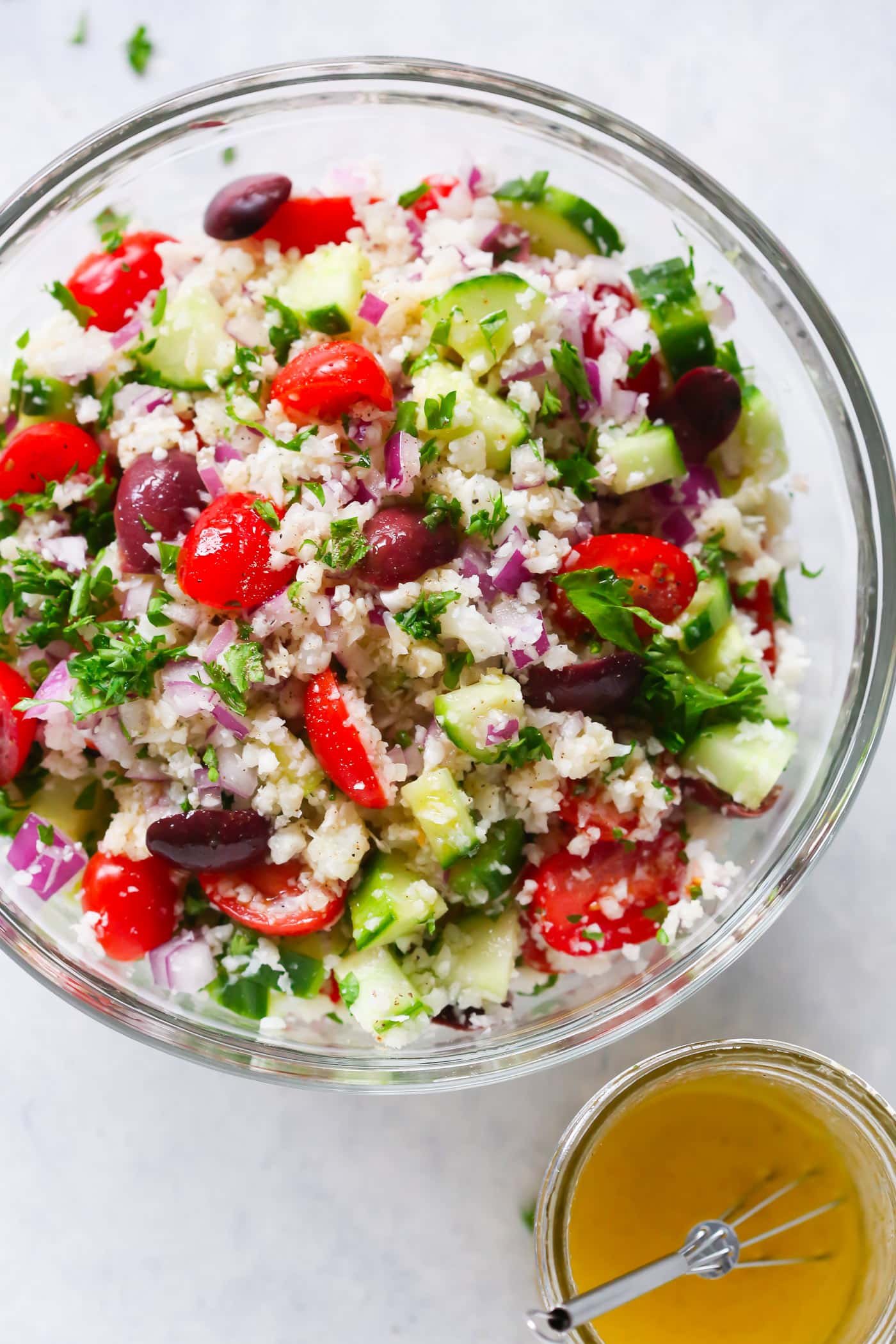 A glass bowl containing cauliflower mediterranean salad. 