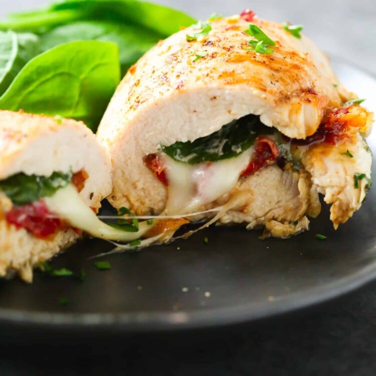 close up of a Sun Dried Tomato, Spinach and Cheese Stuffed Chicken on a black plate