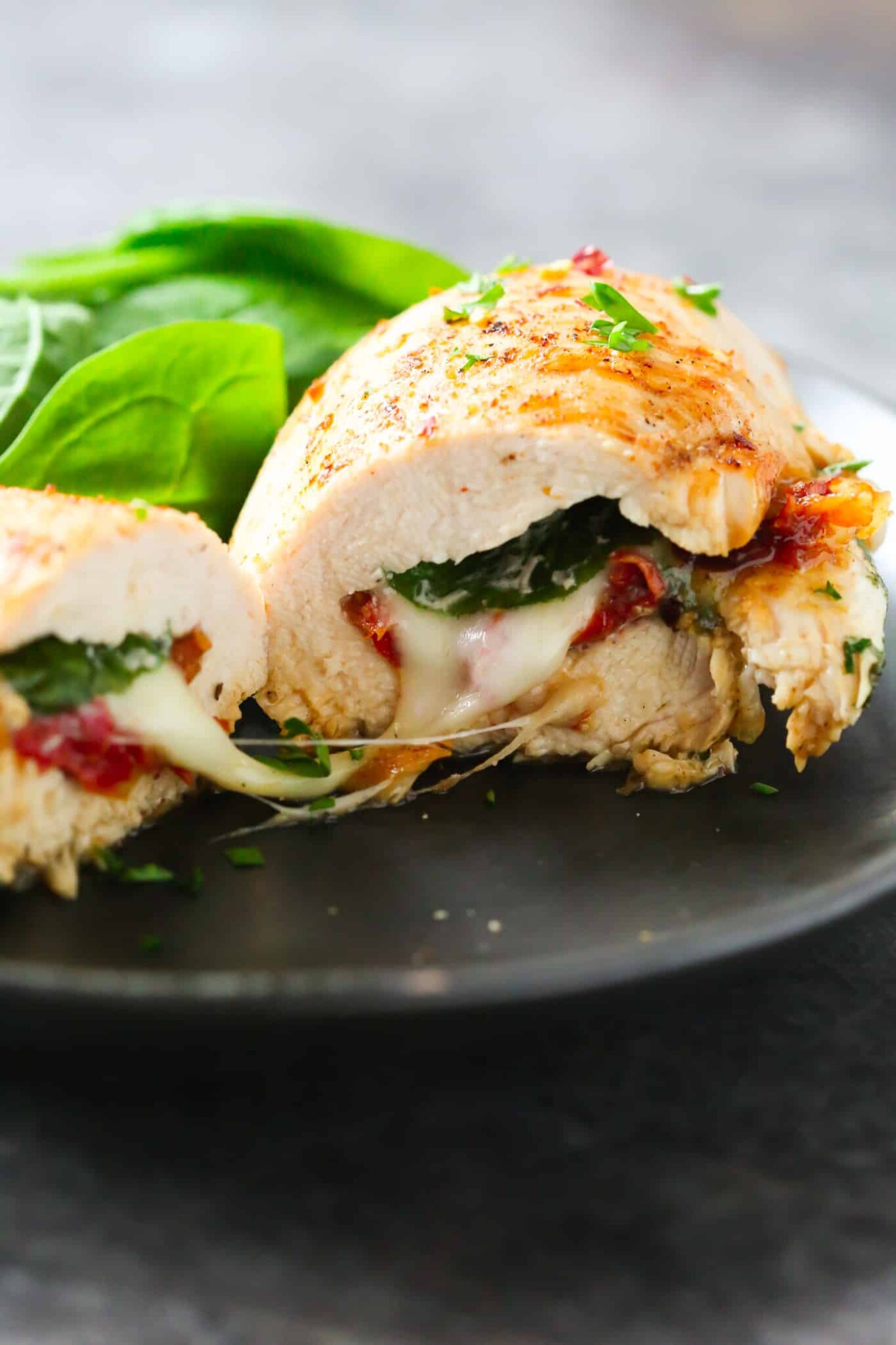 Spinach stuffed chicken breast cut in half on a plate.