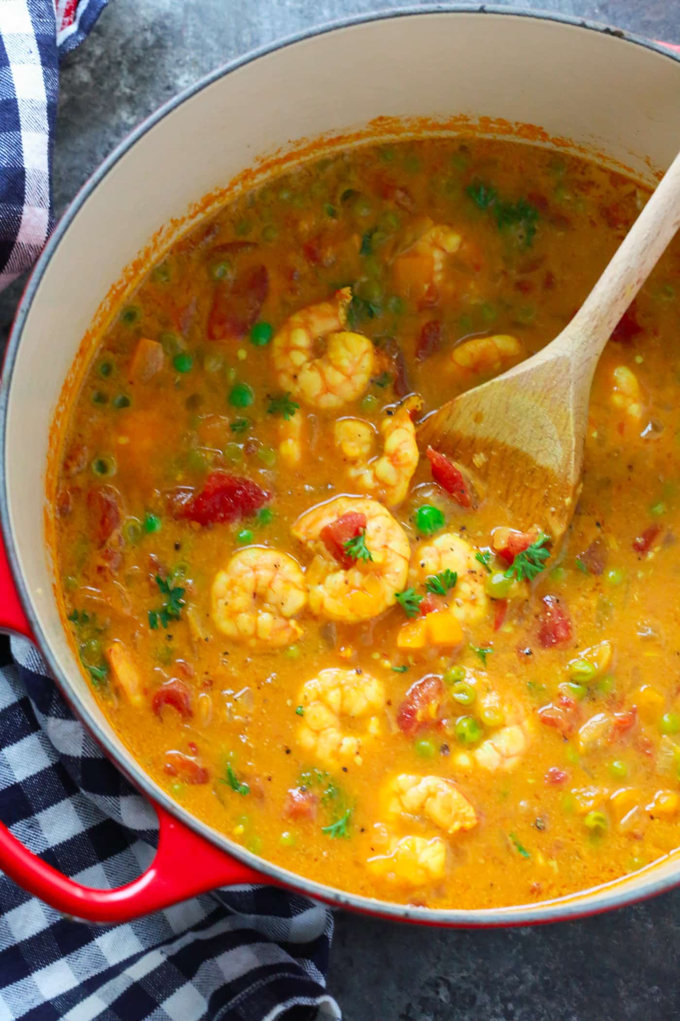 A red dutch oven with a coconut curry shrimp recipe inside.
