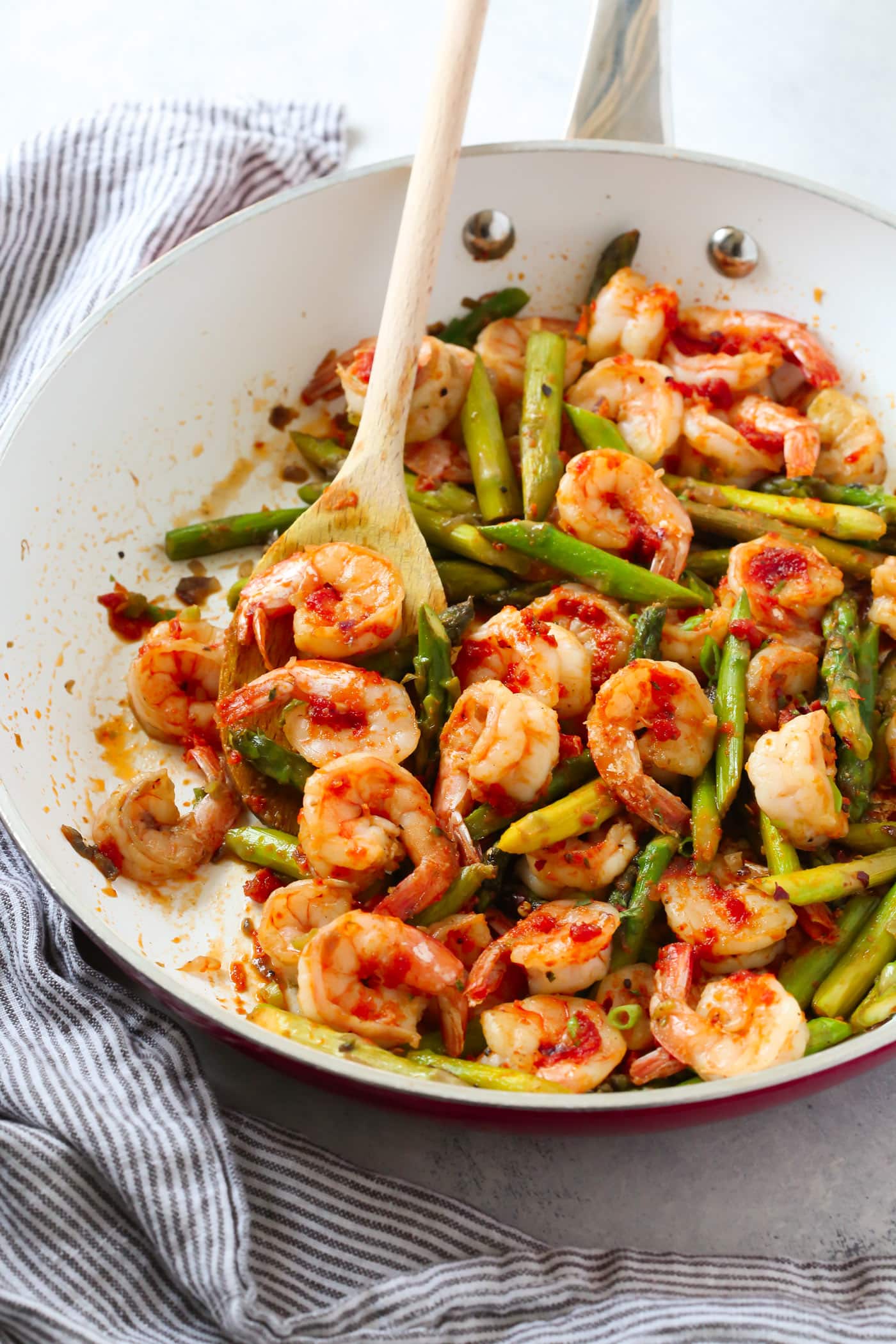 closeup view of asparagus and shrimp in a white skillet