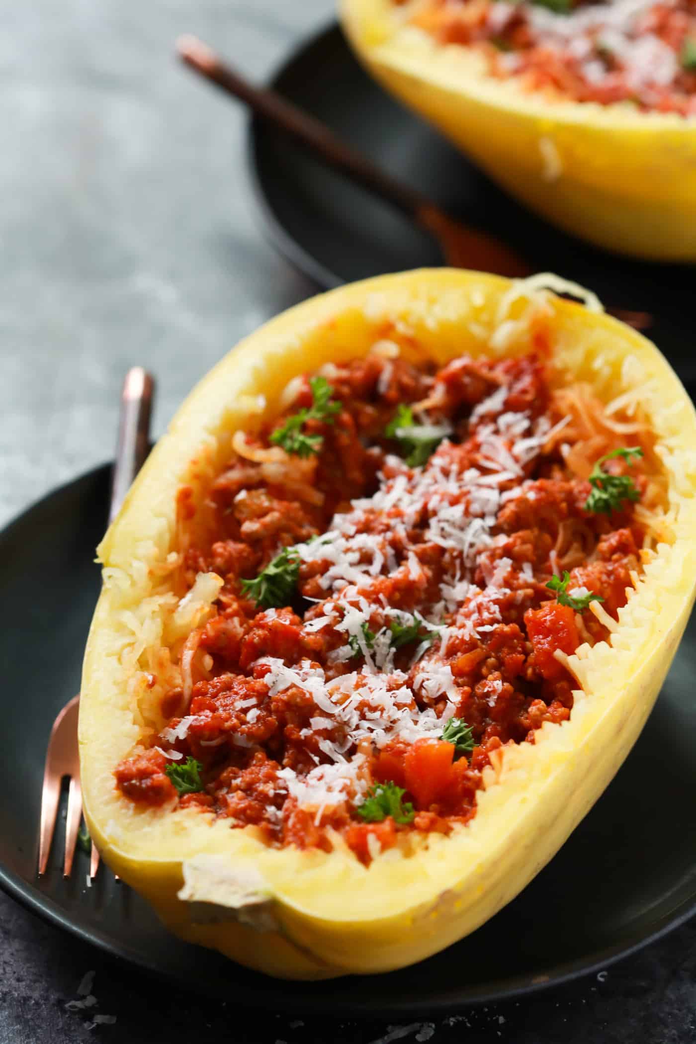 Close-up of spaghetti squash with Bolognese sauce on a black plate.
