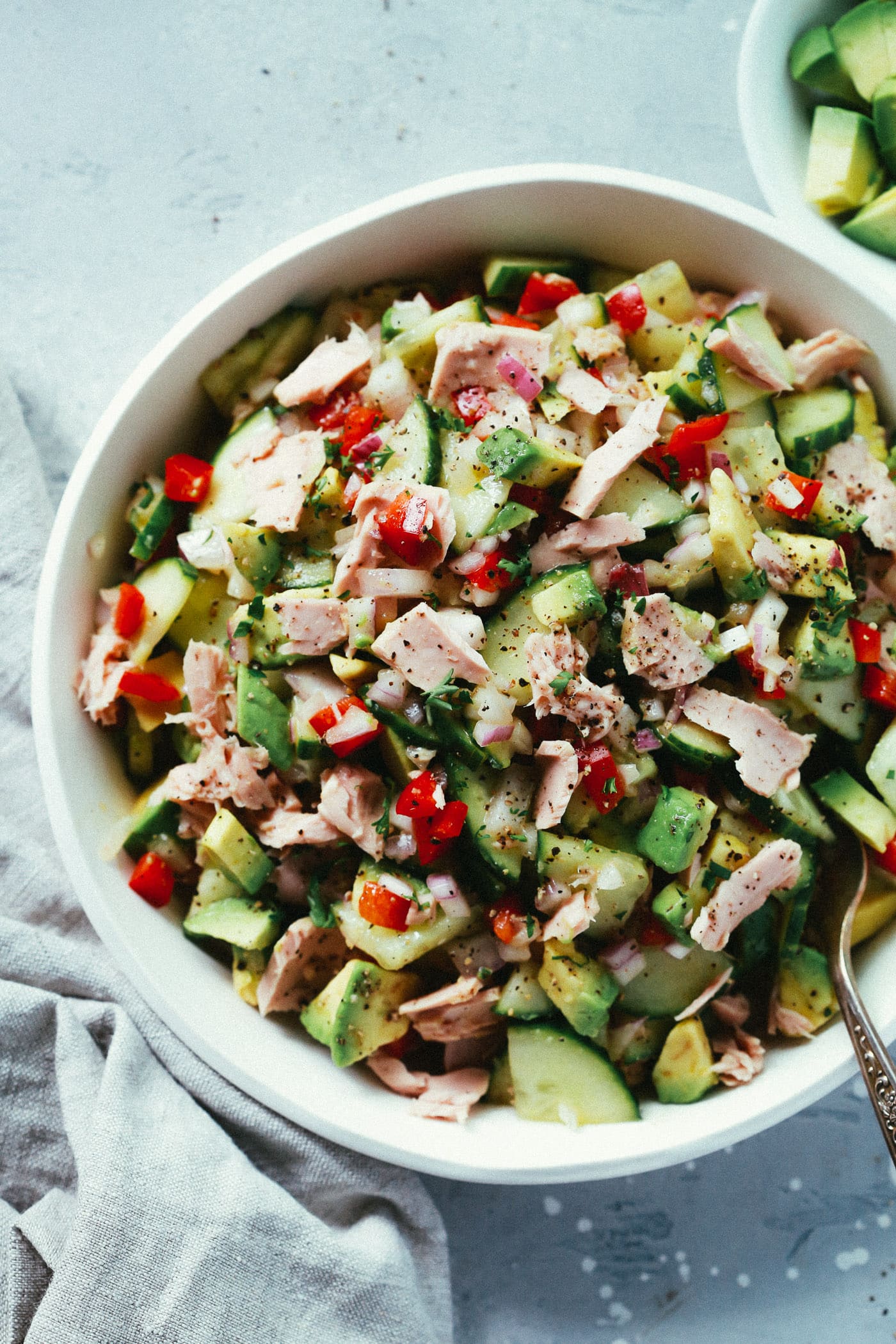 Overhead photo of a white bowl of avocado tuna salad.