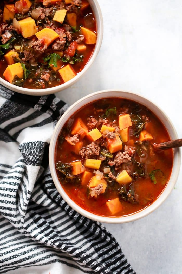 overhead view of sausage and butternut soup in a white bowl