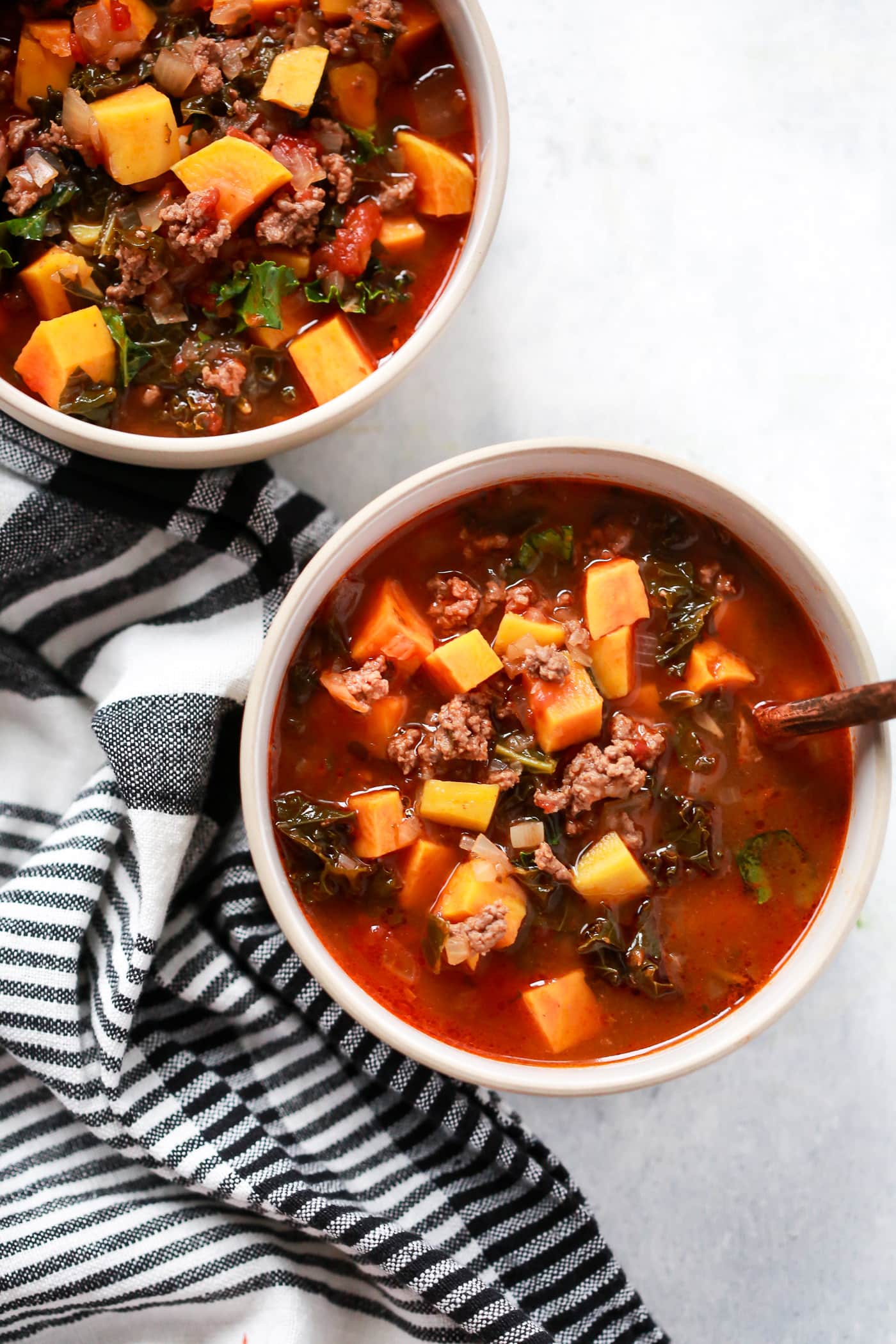 overhead view of two bowls containing Ground Beef Butternut Squash Kale Soup 