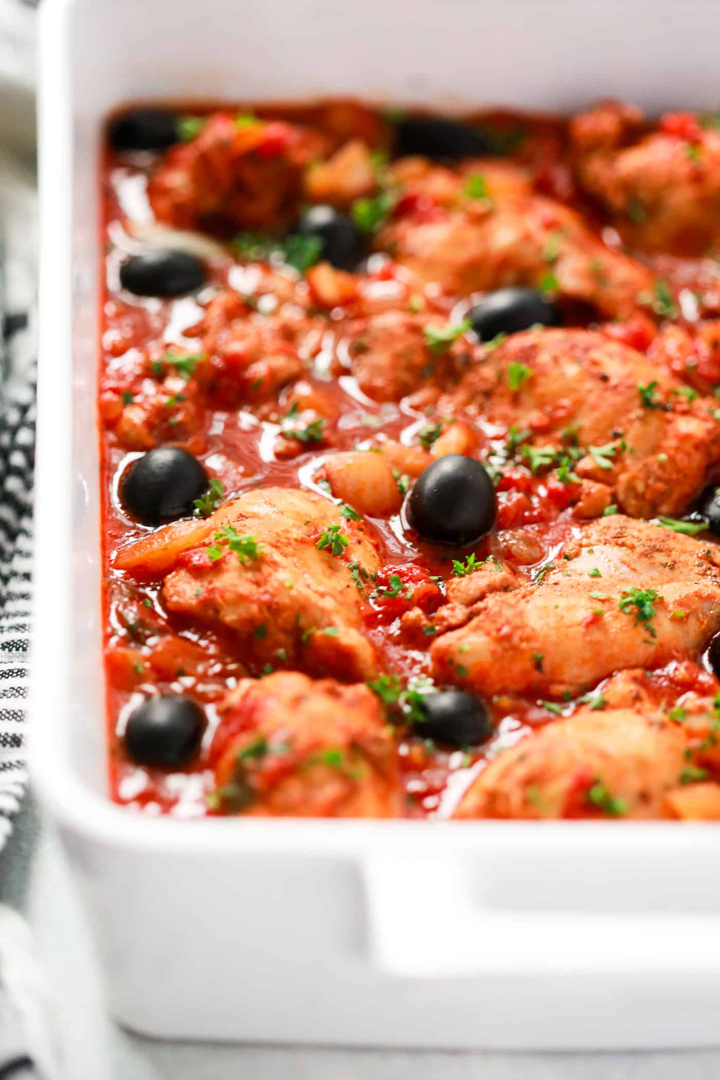 Chicken with tomato sauce in a white serving dish
