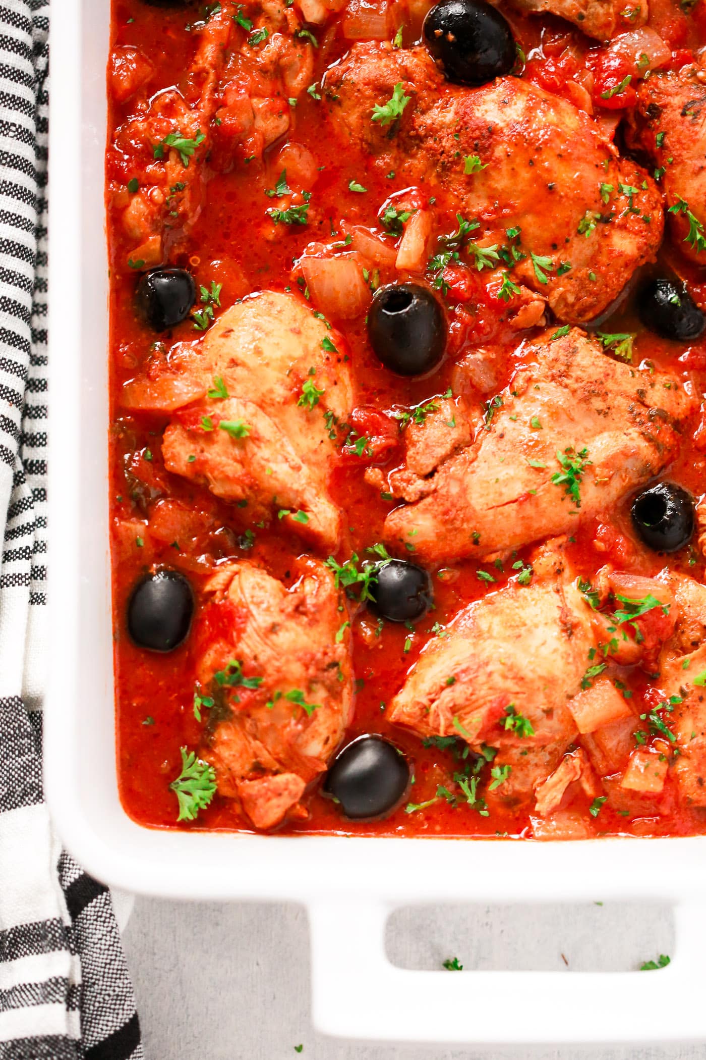 Chicken and tomato sauce in a white serving dish.

